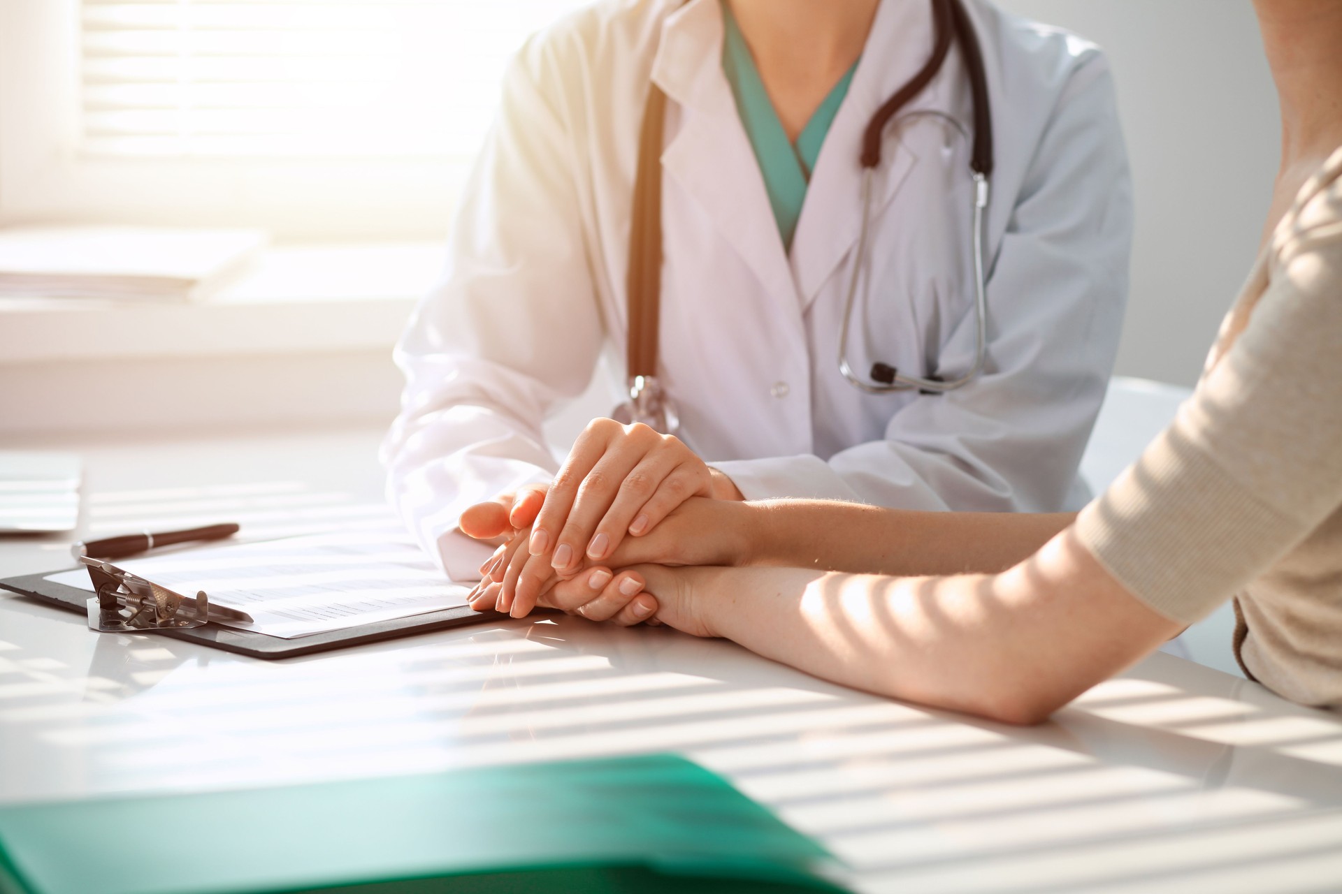 Doctor reassuring patient woman while sitting at the desk in clinic, just hands. Medicine and best service concept